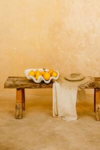 Elegant rustic bench with a textile and citrus decor in a minimalist archway setting.